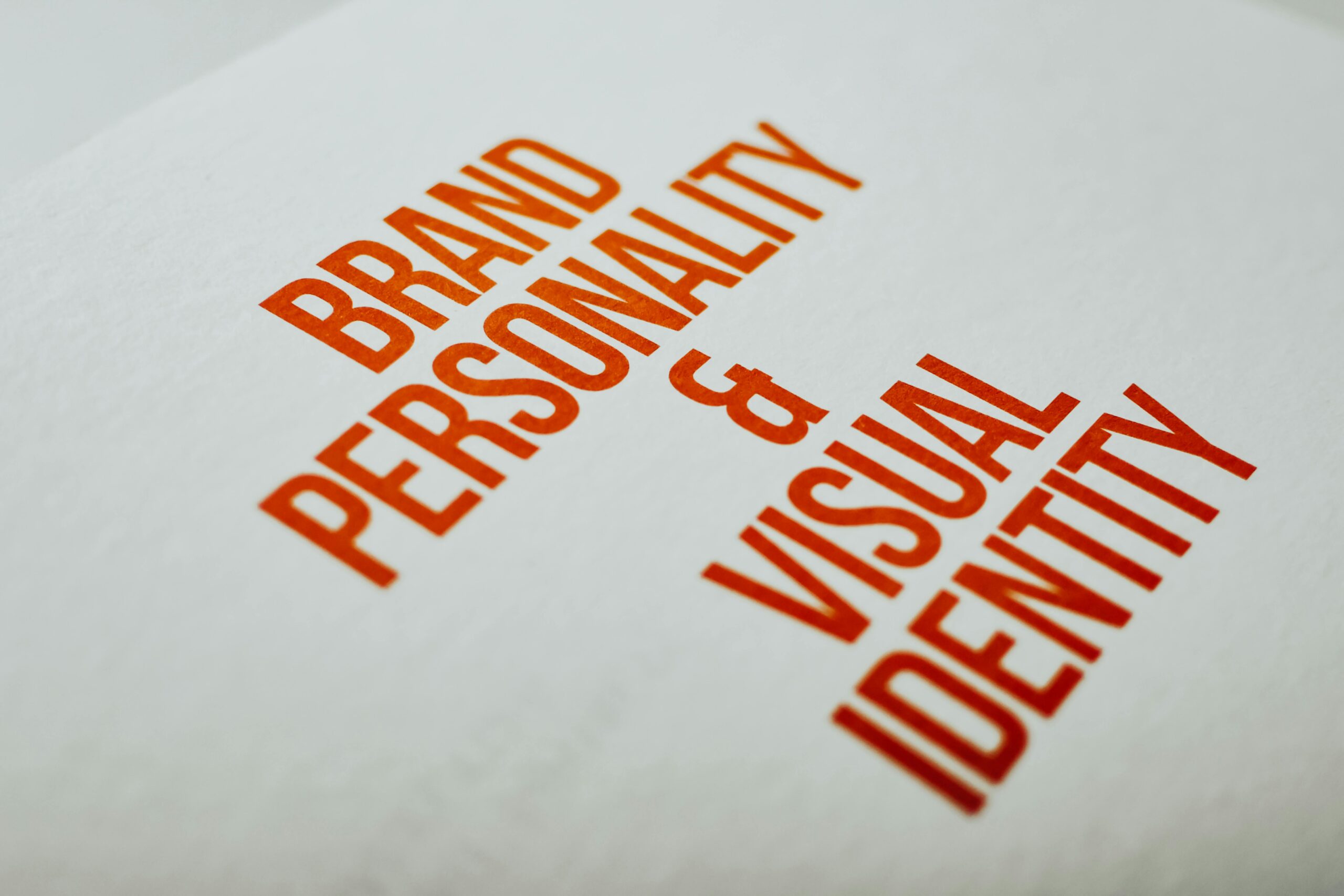 Brand personality and visual identity printed in bold orange text on white paper