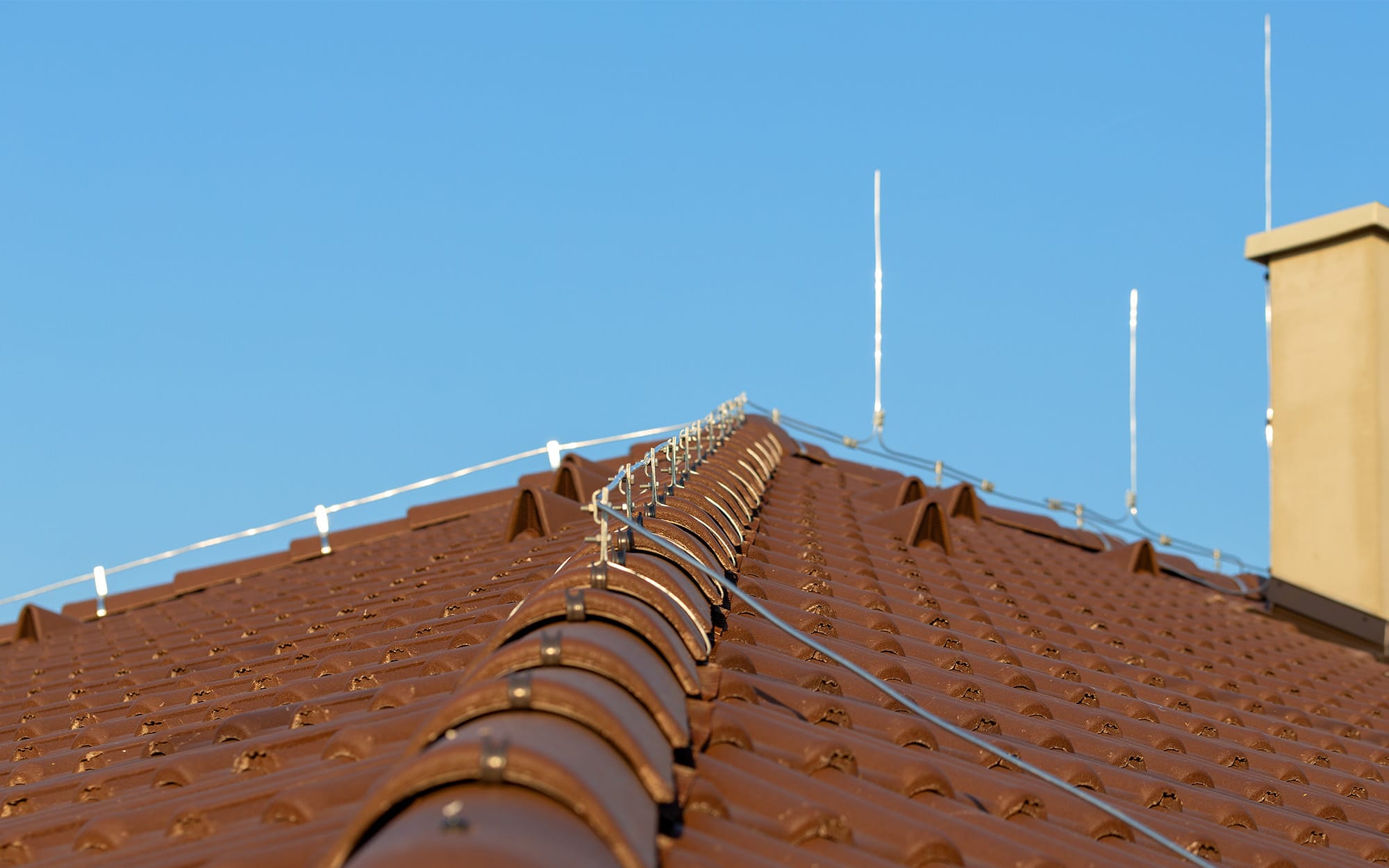 Tile-roof-with-chimney-and-lightning-protection-system-installed.-Lightning-rods.-Close-up-shot.-Lightning-conductor