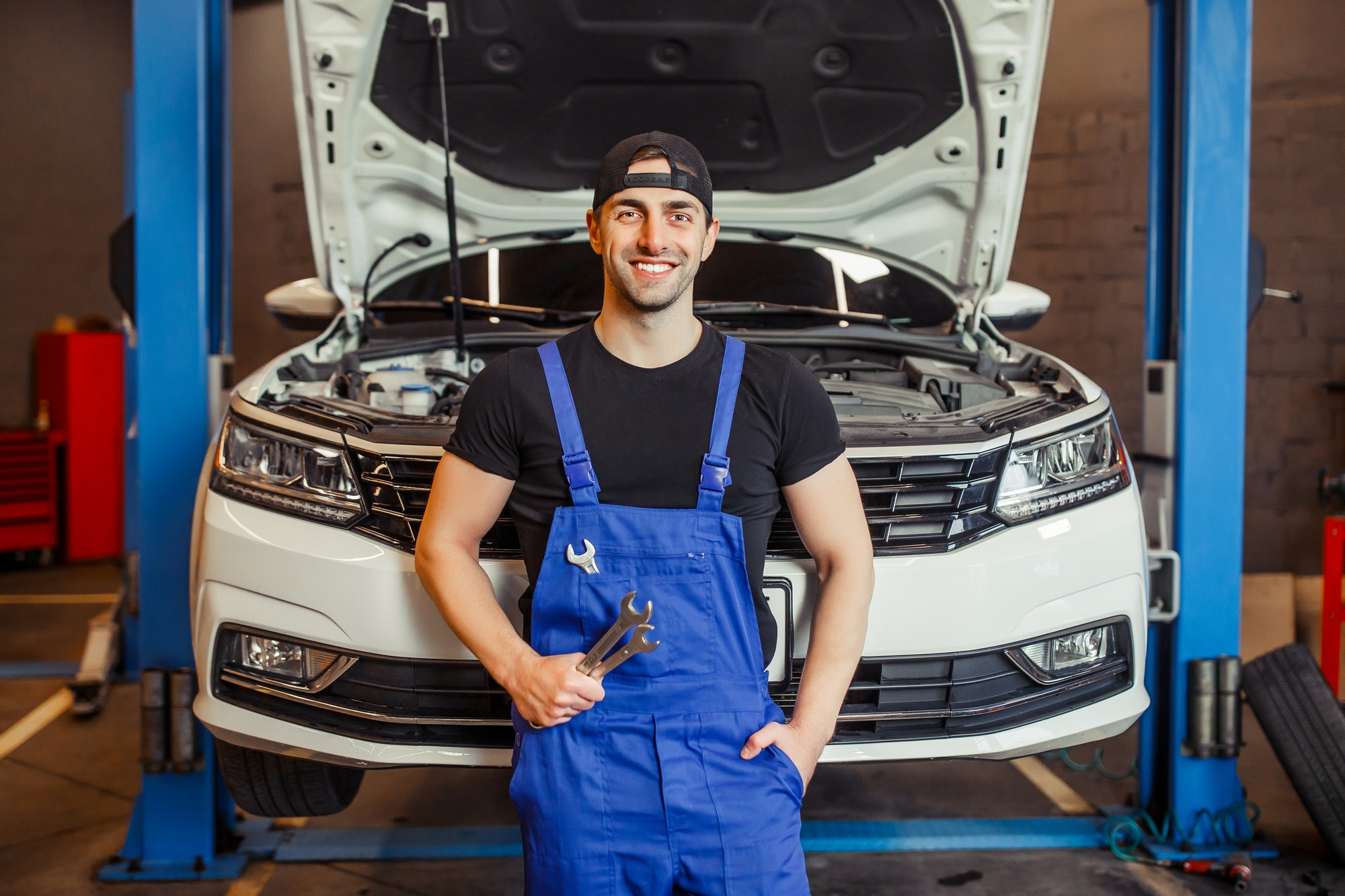 a professional mechanic standing in front of a car.